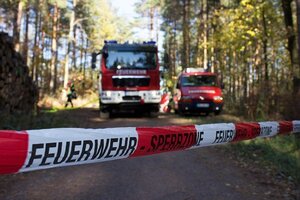 Rotwei�es Flatterbandmit der Aufschrift Feuerwehr Sperrzone �ber einer Stra�e und zwei Feuerwehfahrzeuge im Hintergrund