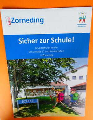 Titelbild der Broschre "Sicher zur Schule" zu sehen ist die Grundschule Zorneding mit gemalten Kindern, die zur Schule gehen.